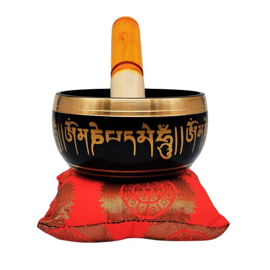 Tibetan singing bowl on red cushion with striker, front view
